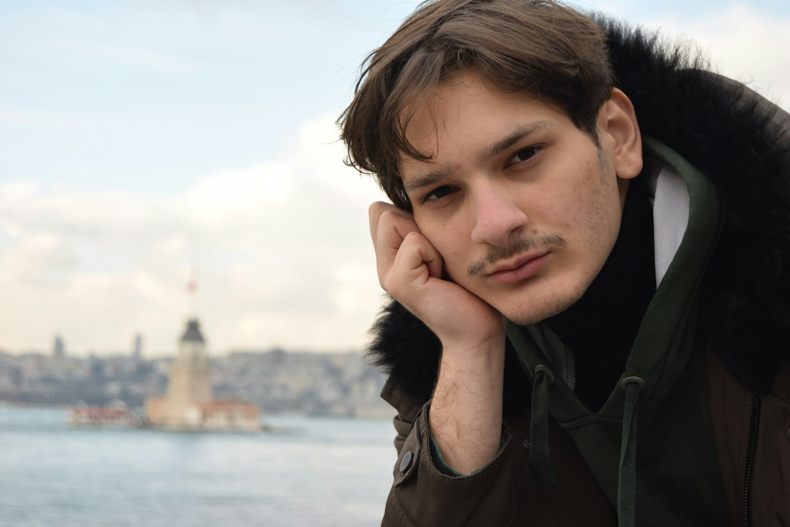 Su kənarında fikrə dalmış gənc